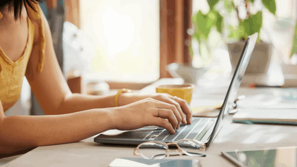 A woman sitting at a desk, using a laptop to find the best blogging platforms to make money.