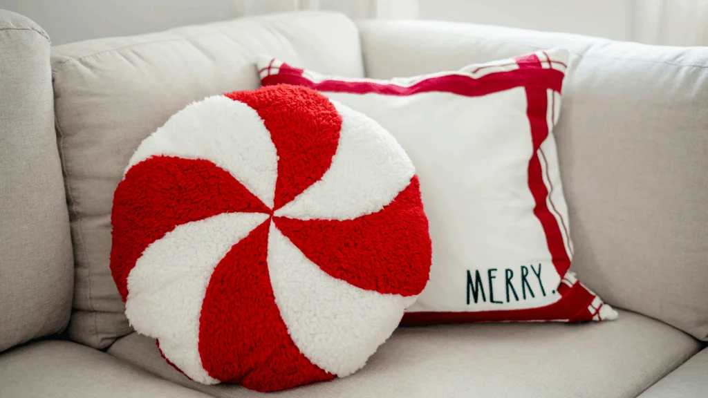 A red and white pillow featuring a decorative Christmas candy cane design.