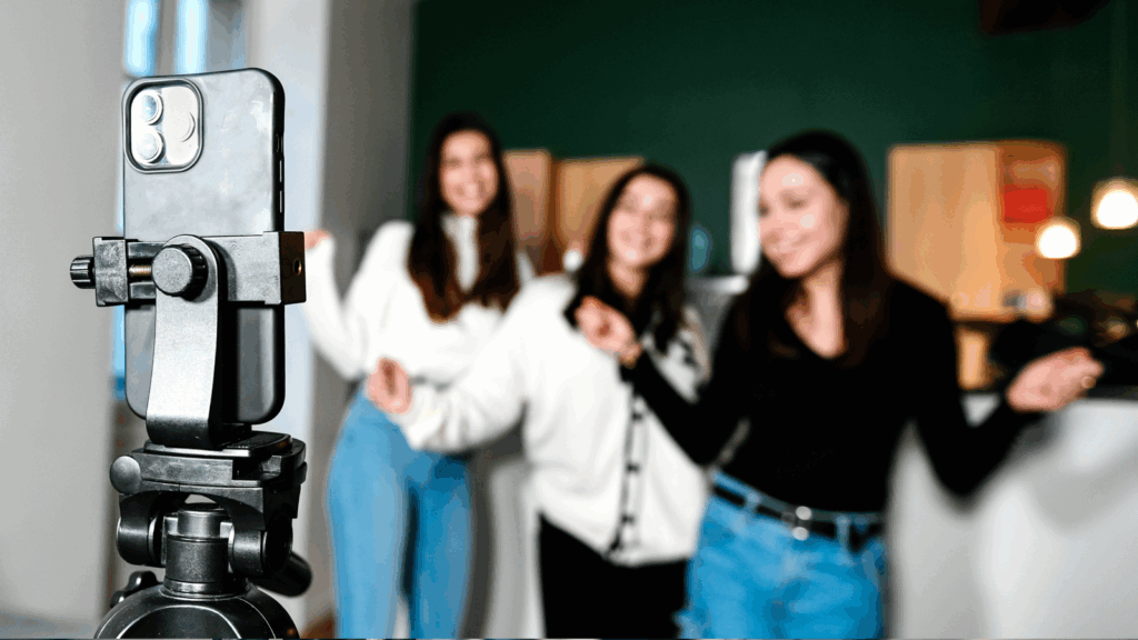 A woman filming a video with her friends, all smiling and enjoying their time together.