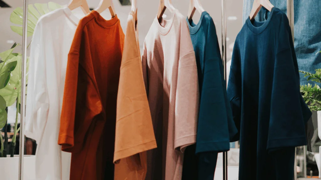 Colorful t-shirts displayed on hangers in a clothing store, showcasing a variety of styles and vibrant hues.