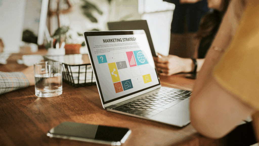 A laptop displaying a marketing strategy document with graphs and text on the screen.