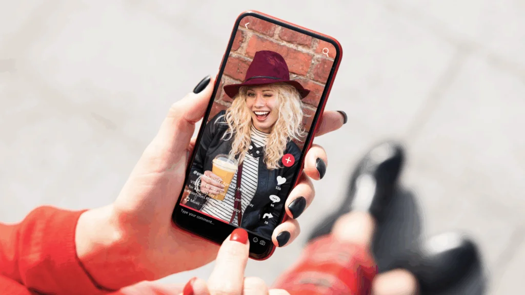 A woman smiles while holding a smartphone displaying her selfie.