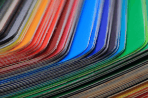 A vibrant stack of paper swatches with rounded edges displays a spectrum of colors, from red and orange to green and blue.