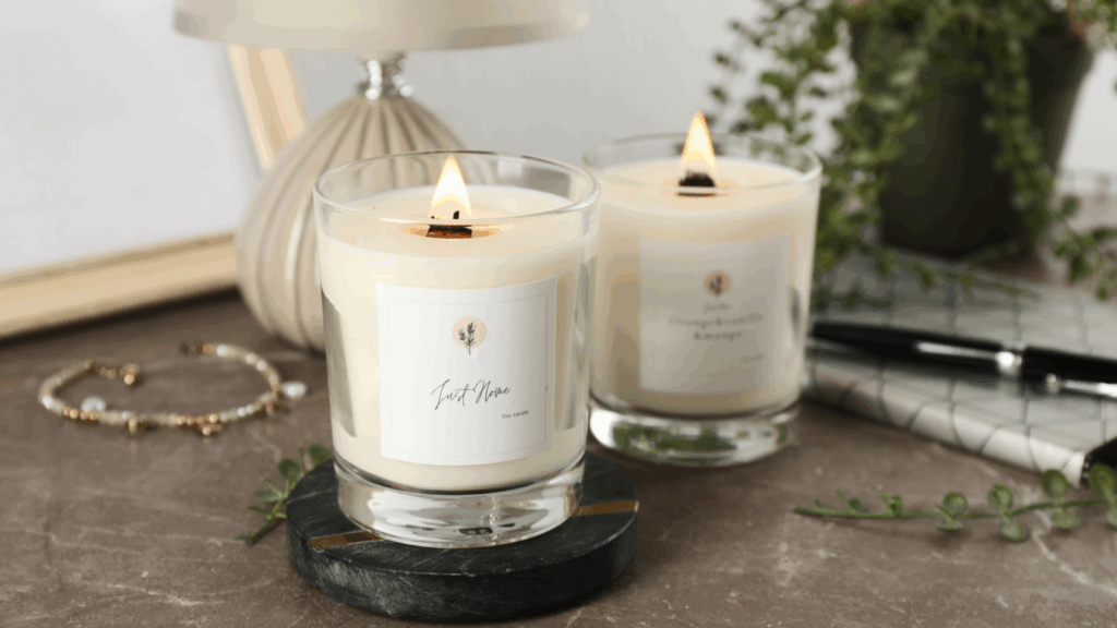 Two lit candles on a table beside a small green plant, creating a warm and inviting atmosphere.