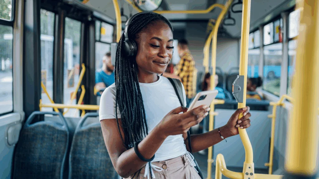 A woman wearing headphones, holding a cell phone, appears focused and engaged in a conversation or listening to music.