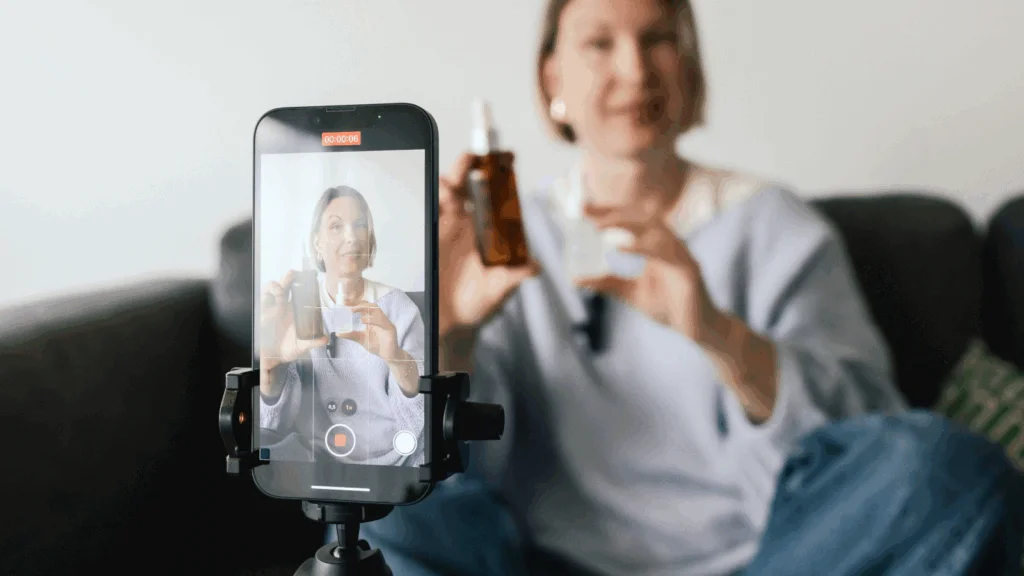 A woman holds a smartphone with a video camera, preparing to record a video.