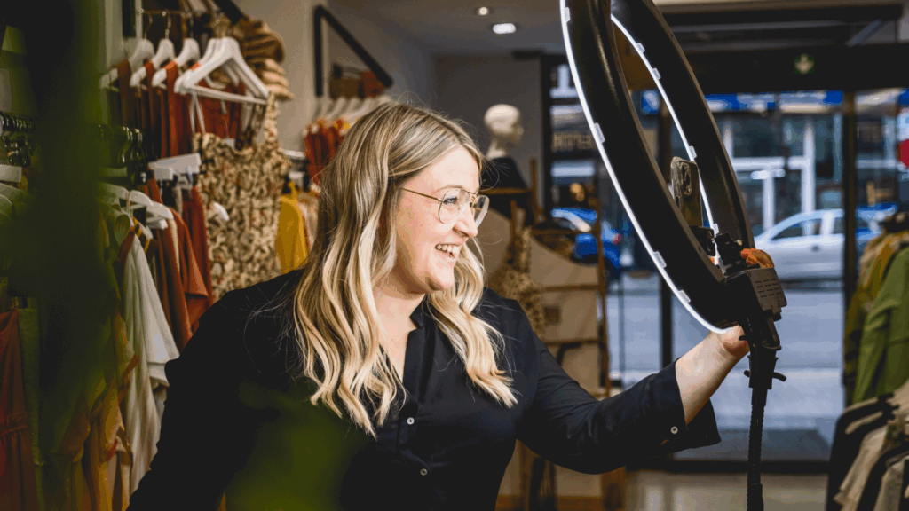 A woman holding a camera in a well-lit room.