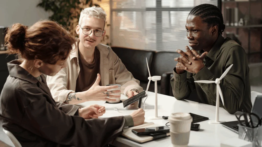 Three individuals seated at a table, collaborating over a laptop during a discussion.