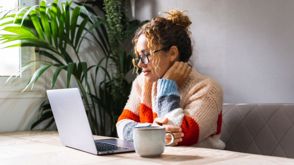 5 Practical tips for creating your flag A woman seated at a table, focused on her laptop, with a calm expression in a well-lit room.