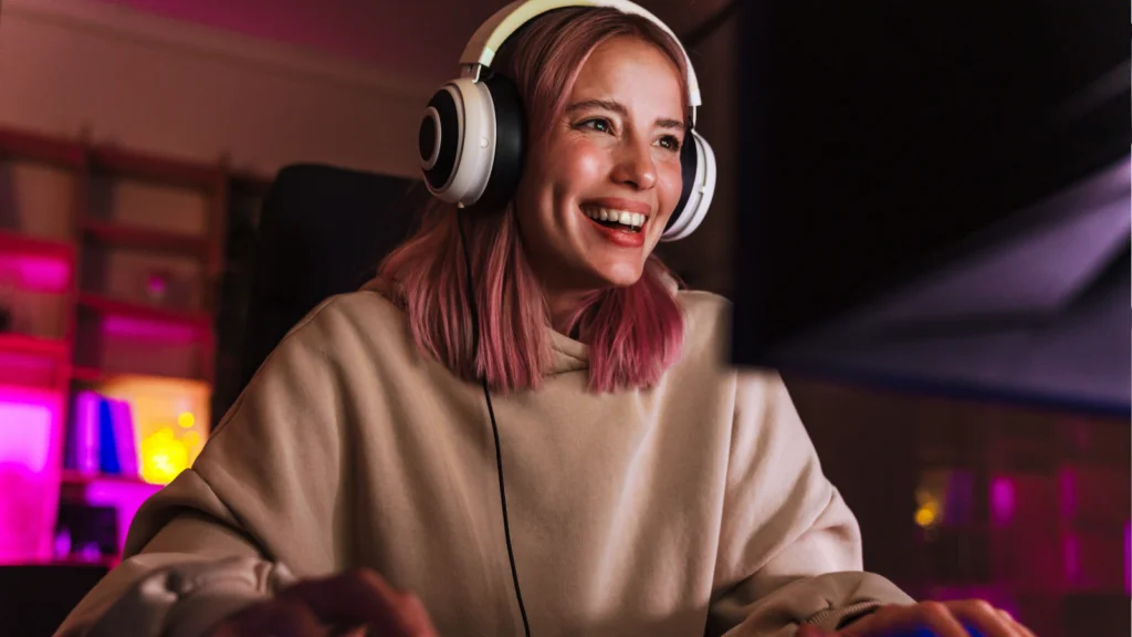 A woman with headphones smiles while engaged in playing video games, showcasing her enjoyment and focus.