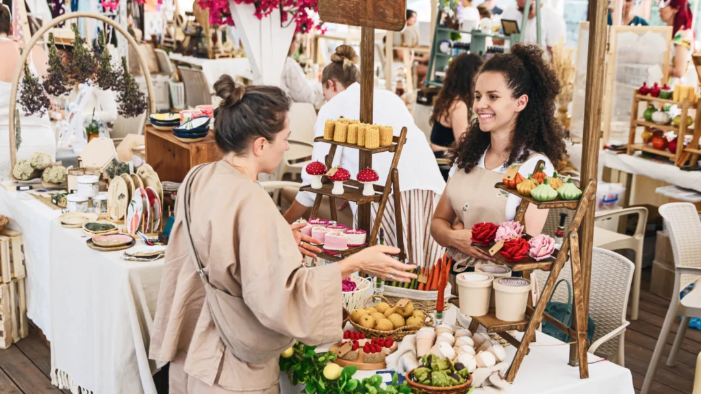 Two women stand at a table filled with various dishes, engaged in conversation and enjoying the meal together.