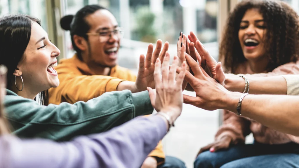 A group of people sitting together, enthusiastically giving each other high fives in a celebratory atmosphere.