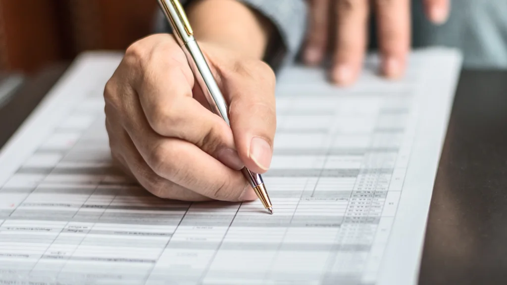 Step 1 Choose and register your business structure A man's hand holding a pen, writing on a sheet of paper.