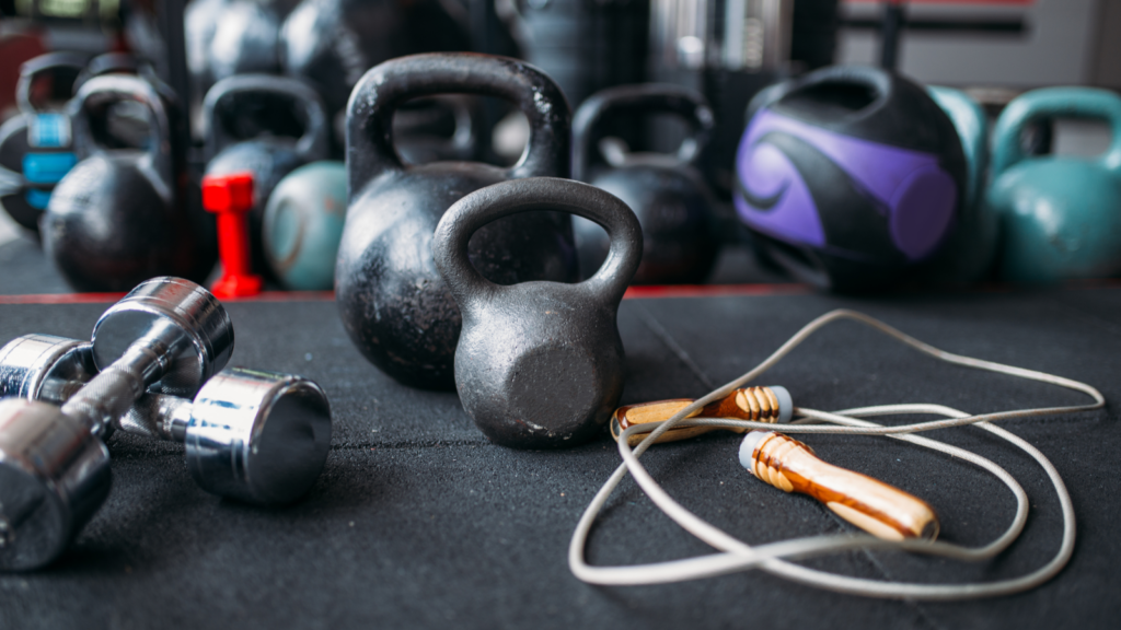 A selection of kettlebells and dumbbells arranged on a black surface, showcasing various weights and sizes.