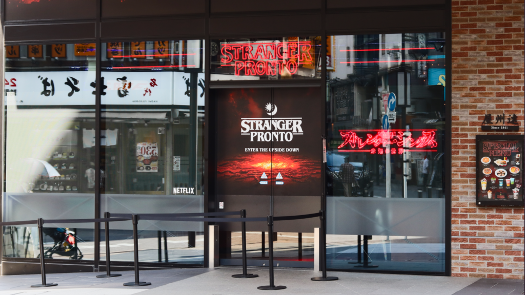 A restaurant exterior featuring a sign that reads "stranger pronto" prominently displayed in front of the building.