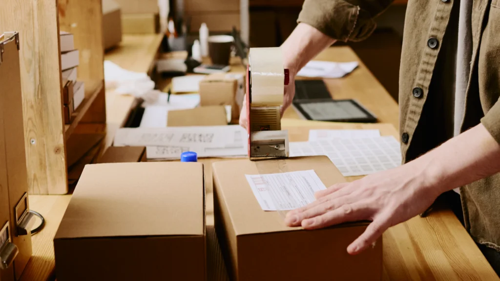 A person applying tape to a cardboard box, preparing it for shipping or storage.