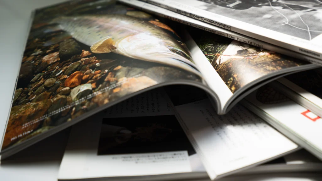 A close-up of several open magazines stacked haphazardly, featuring images of nature.