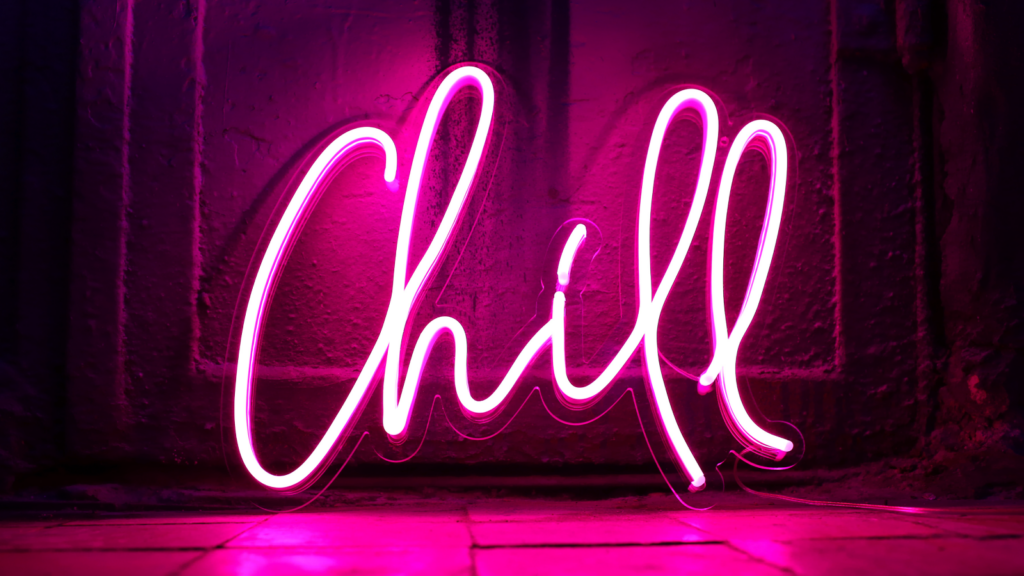 06 Personalized neon signs A bright pink neon sign spells "Chill" in cursive against a dark wall.