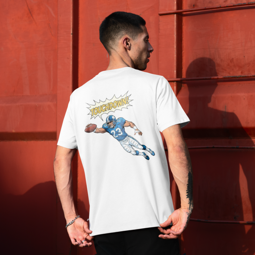 07 Comic book touchdown action scene A man wearing a white t-shirt with a cartoon football player diving for a touchdown. The man stands against a red wall.