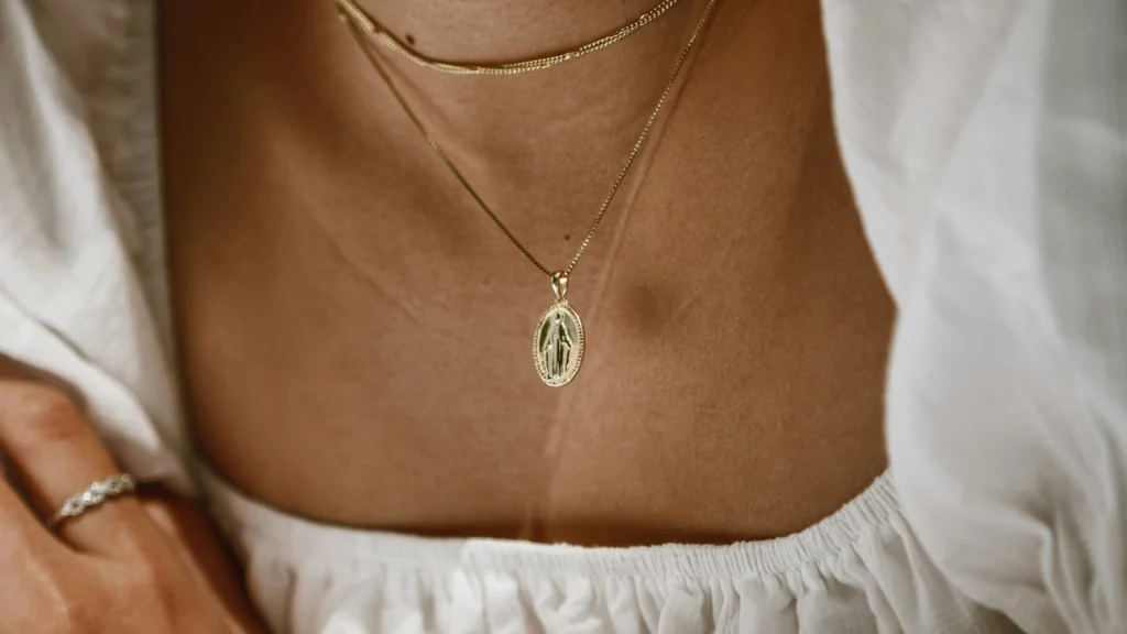 A woman wearing a gold necklace featuring a small coin pendant, showcasing elegance and style.