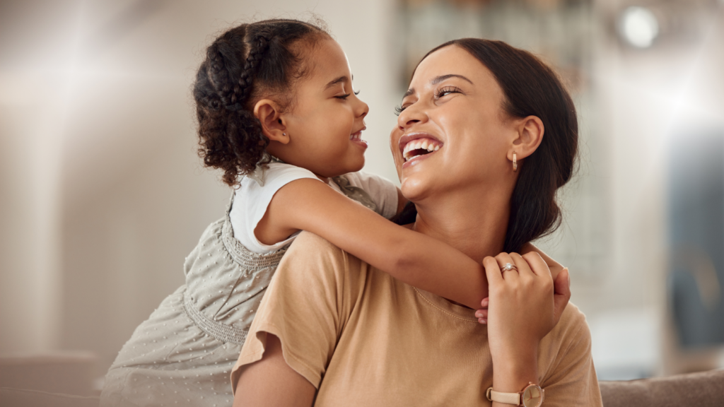 A woman and her daughter share a joyful moment, smiling and laughing together.