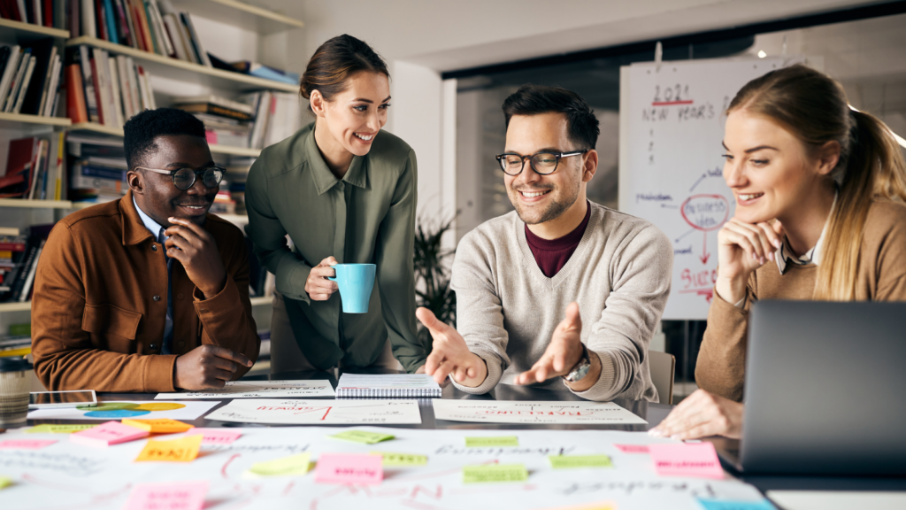 A diverse group of people collaborating around a table covered with colorful sticky notes.
