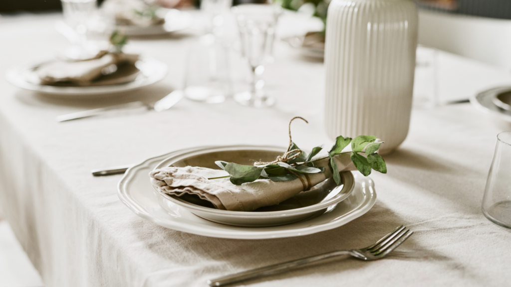 A neatly arranged table setting featuring white plates and polished silverware.