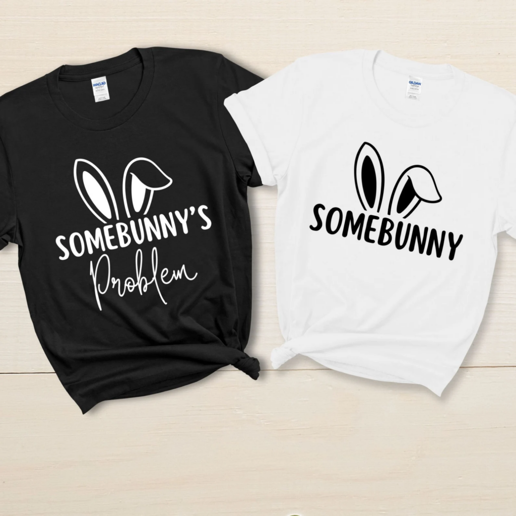Left: black t-shirt with white text "Somebunny's Problem" and bunny ears. Right: white t-shirt with black text "Somebunny" and bunny ears.