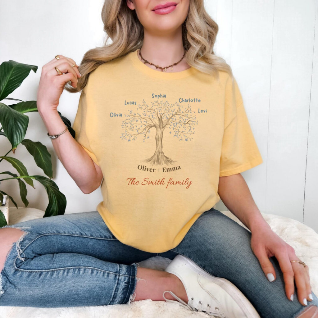 A woman in a yellow t-shirt with a family tree design sits cross-legged. The shirt features names and the phrase "The Smith family".