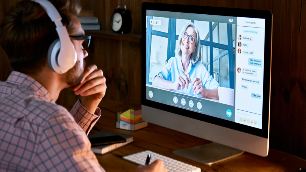 A man wearing headphones is engaged in an online class led by a woman.
