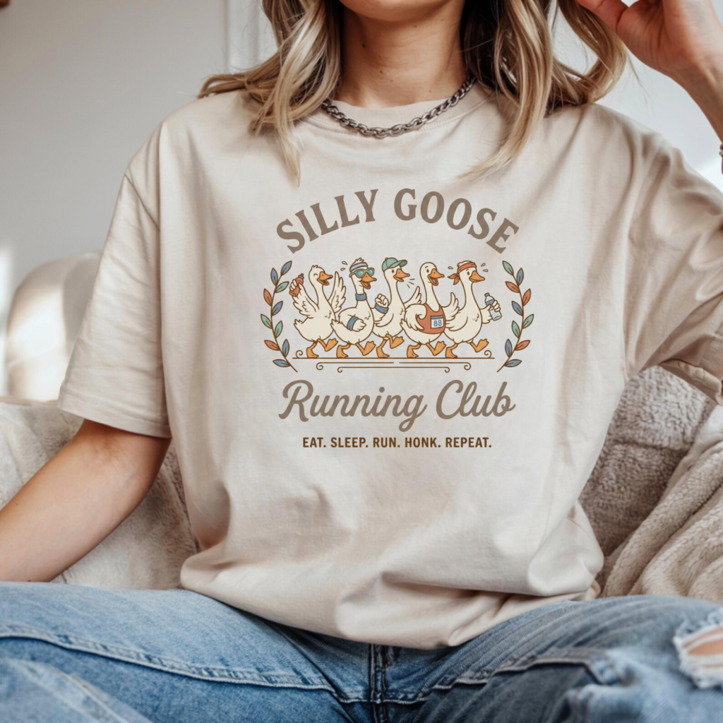 Woman wearing a beige t-shirt with cartoon geese and the text "Silly Goose Running Club: Eat. Sleep. Run. Honk. Repeat.".