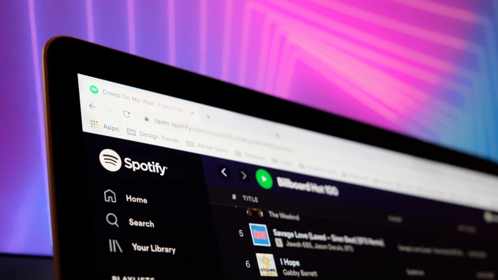 Laptop screen displaying Spotify's web interface with playlists visible.