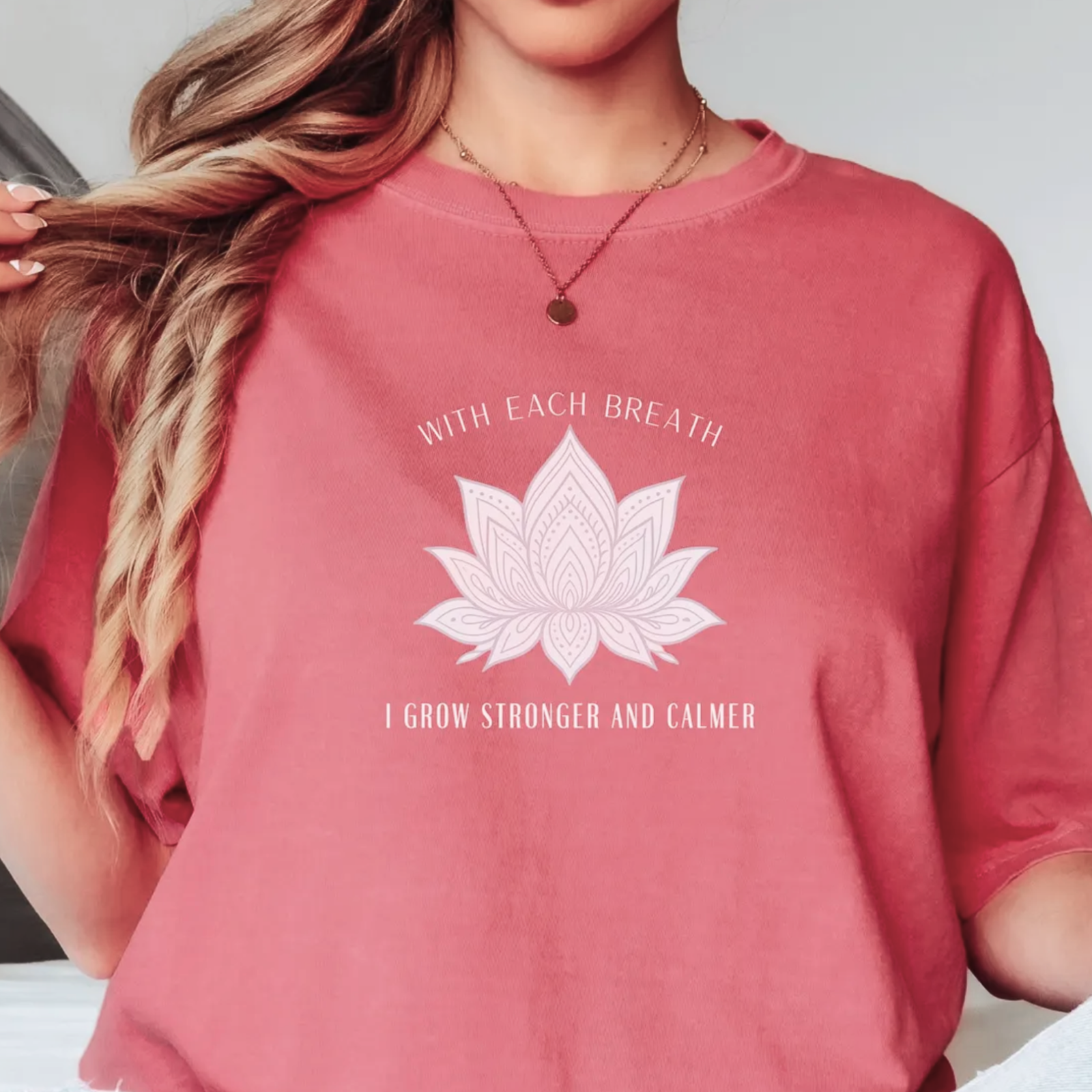 Woman in a pink shirt with a lotus design that reads, "With each breath, I grow stronger and calmer."