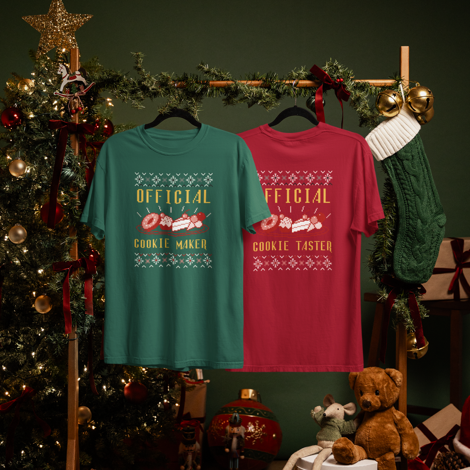 Two festive T-shirts hang on a wooden rack adorned with garland.