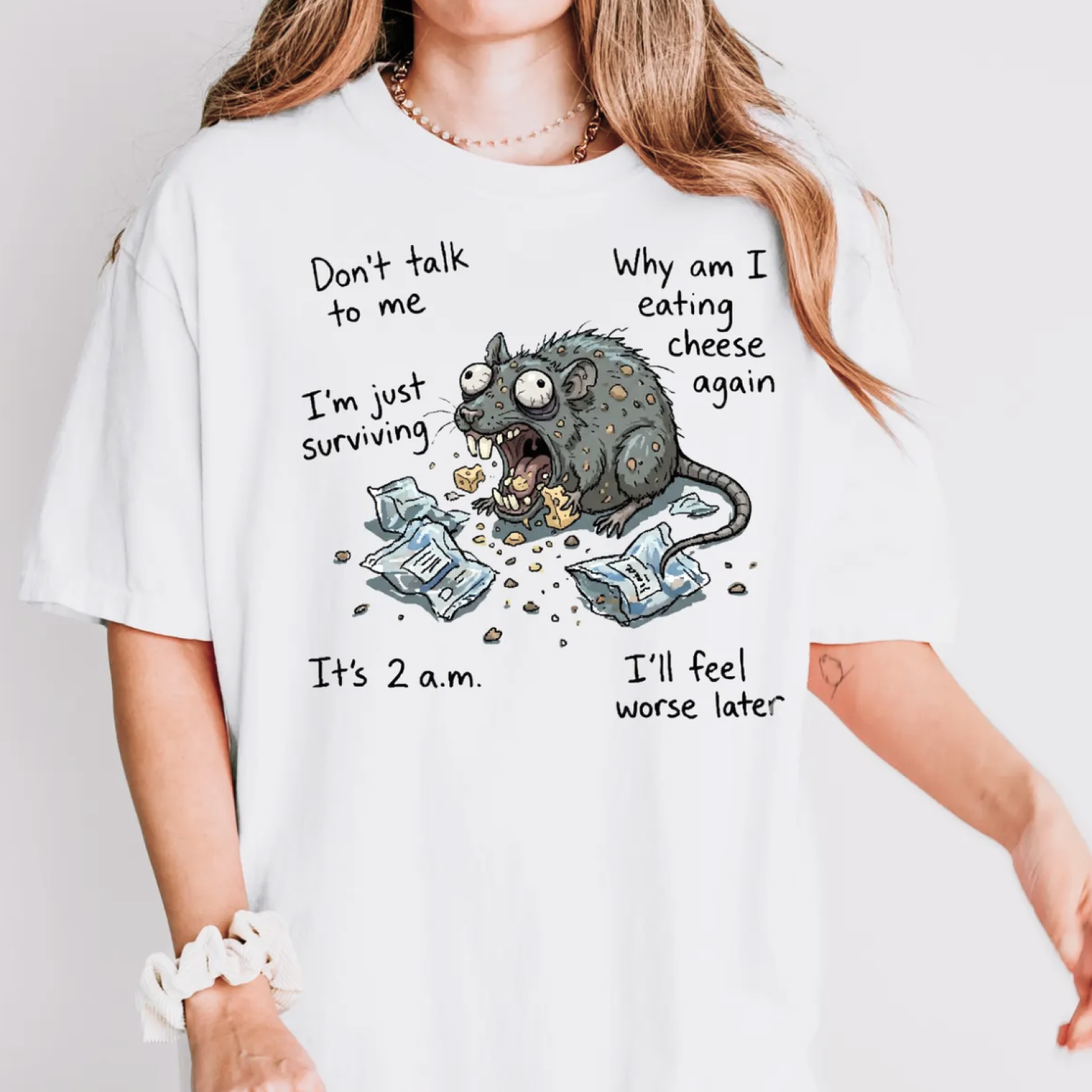 A woman is wearing a white t-shirt featuring a humorous cartoon rat eating cheese amid torn packages.