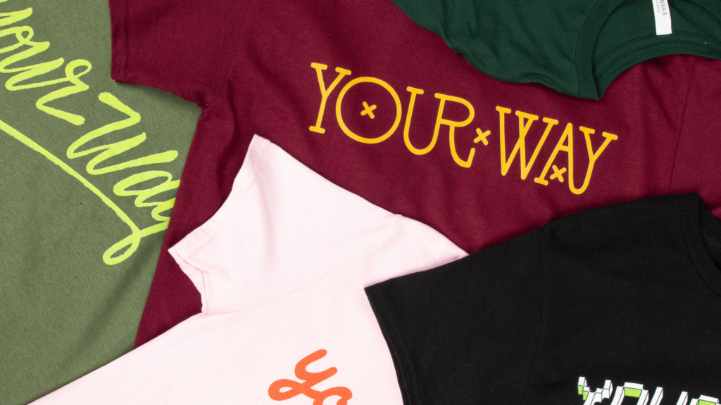 Order quantity Multiple “Your way” t-shirts stacked on top of each other. T-shirts differ in color and text styling.