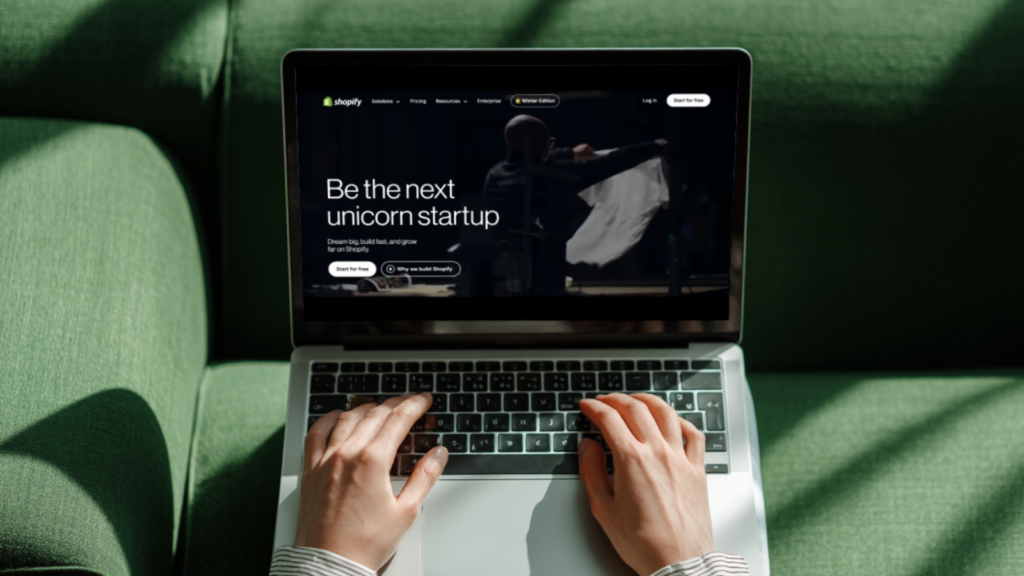 A person using a laptop with Shopify’s homepage on the screen.