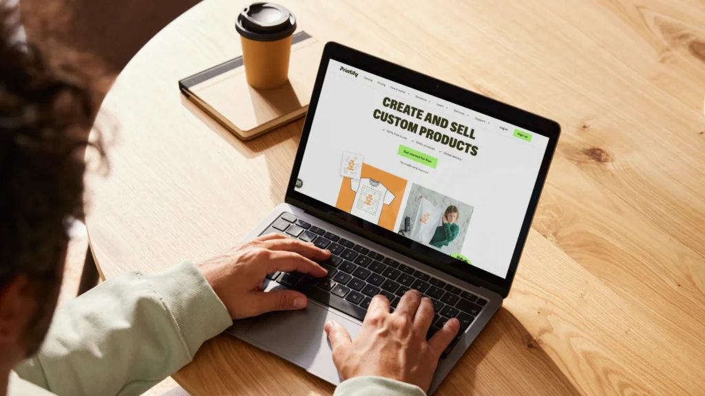 Guarantee fast and reliable fulfillment A person is using a laptop with Printify’s homepage on the screen.