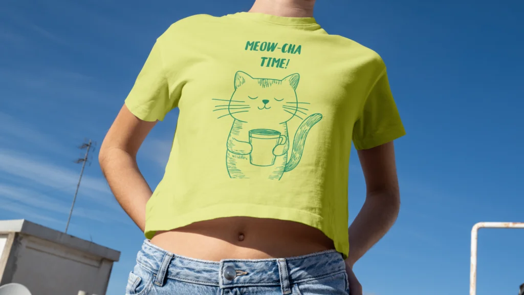 Using product samples to improve affiliate conversions A young woman wearing a yellow “Meow-cha time” t-shirt with an illustrated cat drinking coffee.