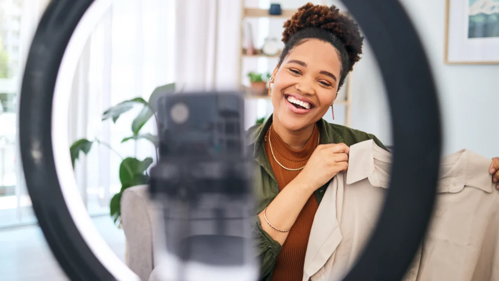 2 How to optimize your TikTok Shop product images A woman smiles while holding a shirt in front of a mirror, reflecting her joyful expression and the shirt's design.