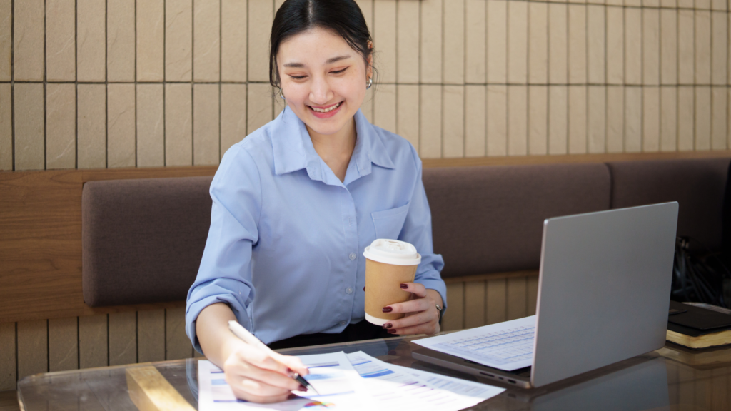 2 Understanding impressions clicks and the conversion gap A woman seated at a table, working on a laptop with a cup of coffee beside her.