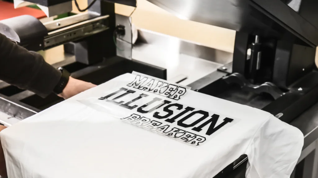 Eco friendly t shirt printing methods A person is preparing to print “Maker Illusion Breaker” text on a white t-shirt.