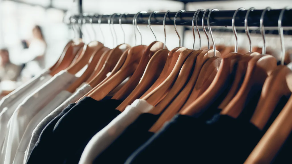 Most profitable clothing niches Clothes of various styles and colors hanging on hangers in a well-organized clothing store.