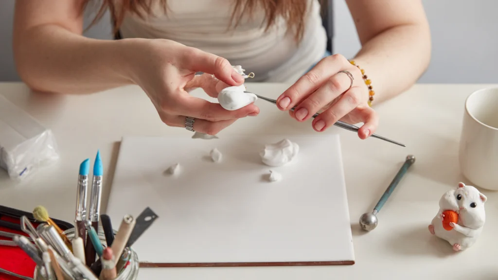 Jewelry thumbnails A woman making hamster figures from white clay.