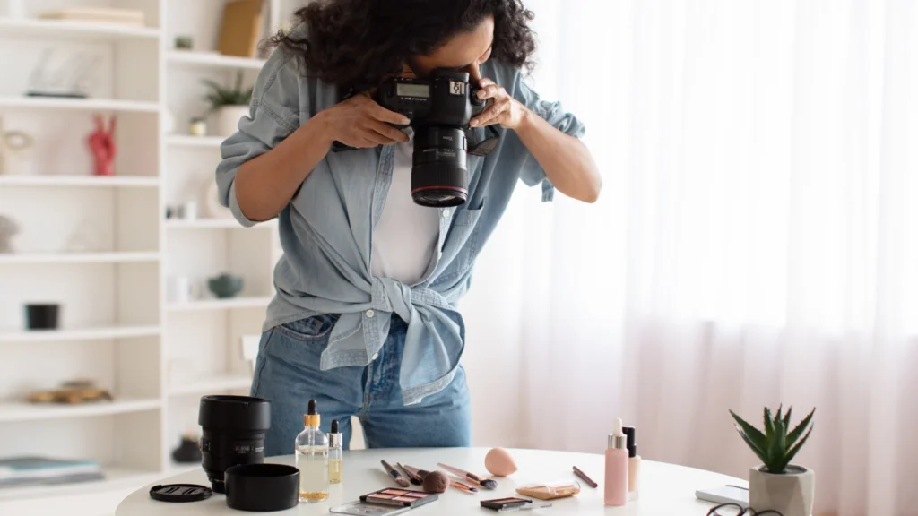 What makes a good Etsy thumbnail A woman is taking pictures of makeup products with a DSLR camera. White shelves with various items in the background.